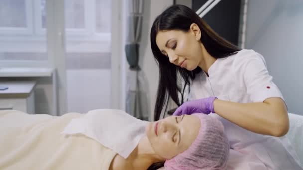 美容师为美容中心的妇女注射药物 病人在手术过程中躺在沙发上 中间治疗 — 图库视频影像
