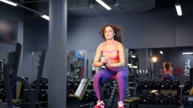 Kadın spor salonundaki tahta kutunun üzerinden atladı. Spor kıyafetli güçlü bir kız egzersiz yapıyor..