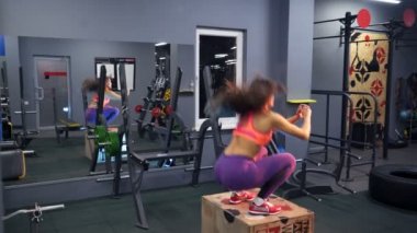 Zıplayan genç kadın kutusuna zıpla. Kadın sporcu spor salonunda kutu atlayışı yapıyor.