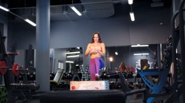 Genç atletik kadın spor salonunda atlama egzersizi yapıyor. Sağlıklı yaşam tarzı.