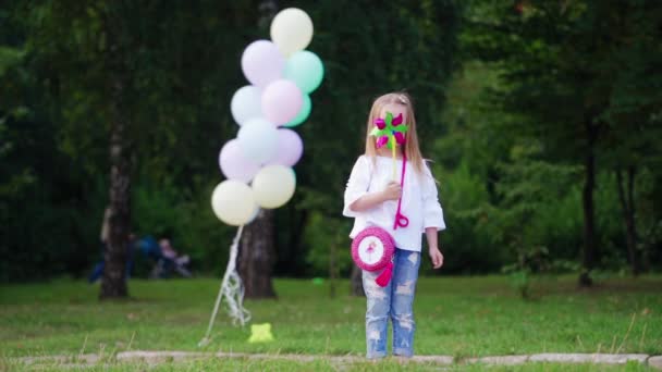 女の子はピンホイールで遊ぶ 夏の日の好色の女の子手で風車を保持 — ストック動画