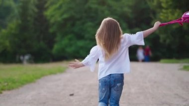 Parkta koşan küçük kız. Mutlu Asyalı küçük kız koşuyor ve parkta eğleniyor.