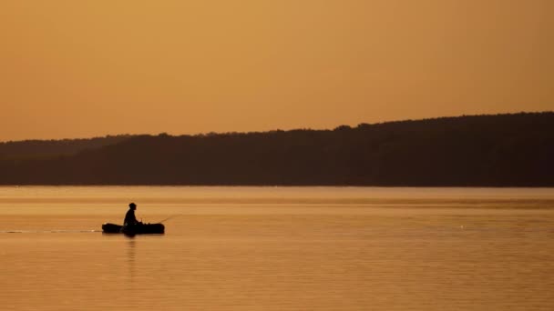 漁船の中の漁師のシルエット 日没時にボートから湖で釣り — ストック動画