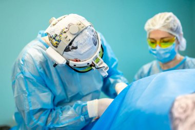 Konsantre cerrahi doktor ve hemşire bir hastayı ameliyat ediyor. Modern klinikte estetik cerrahi. İyi eğitimli tıp uzmanları. Kozmetik ve cerrahi konsepti.