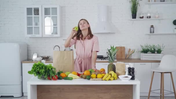 漂亮的女人站在厨房里 在厨房里吃水果的年轻女人 — 图库视频影像