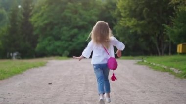 Kız dışarıda eğleniyor. Park 'ta kaçan küçük bir kızın arka görüntüsü.