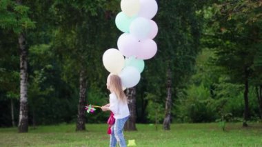 Parkta koşan küçük bir kız. Parkta balonlarla koşan mutlu küçük kız.