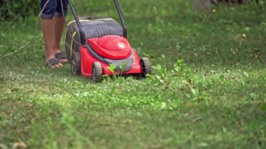 Çim biçme makinesi yeşil çimleri kesiyor. Çim biçme makinesiyle çimleri biçen adama yaklaş.