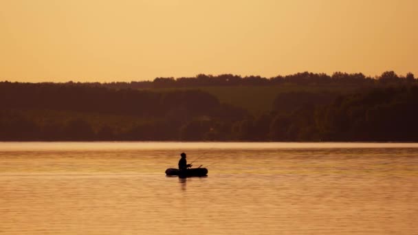 船身轮廓中的渔夫 日落时在池塘边的船上钓鱼的成熟男子 — 图库视频影像