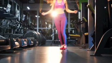 İple atlayan bir kadın. Spor salonunda ip atlama egzersizi yapan genç bir kadın.