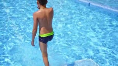 Çocuk yüzme havuzuna dalıyor. Çocuk manzarası çok eğlenceli ve havuza atlıyor.