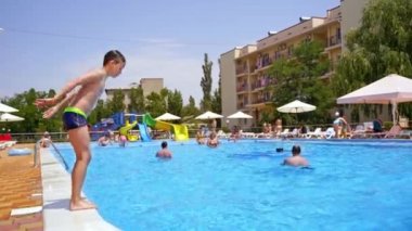 Çocuk havuzda oynuyor. Küçük çocuk yüzme havuzuna atlıyor.