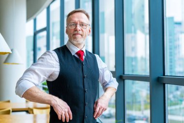 Takım elbiseli düşünceli orta yaşlı iş adamı. Pencerenin yanında duruyor. İş konsepti.