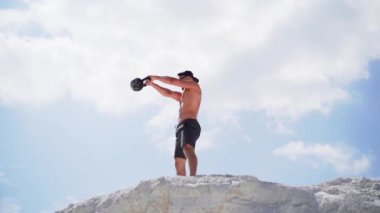 Kettlebell egzersizi yapan bir adam. Atletizm ve açık havada egzersiz.