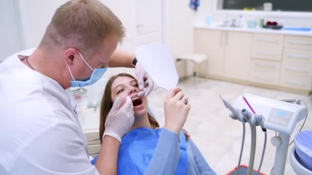 门诊部的牙科程序牙科医生在张嘴的牙椅上检查病人的牙齿 — 图库视频影像
