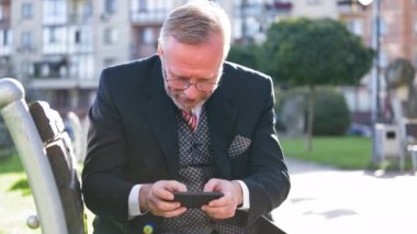 Sakallı adam oyun oynuyor. Telefonda oynayan duygusal kıdemli adam.