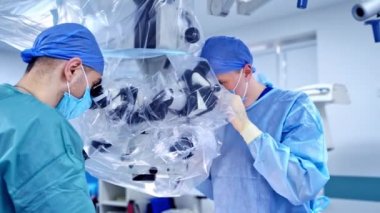 Ameliyathane için modern mikroskop. Ameliyat sırasında mikroskop kullanan bir grup cerrah.