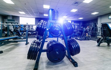 Spor salonundaki bir dambıl için kocaman krepler. Spor ve sağlıklı yaşam konsepti. Beden eğitimi arka planında krep seti. Spor ekipmanları yakın plan..