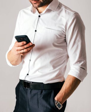 Beyaz gömlekli, cep telefonu kullanan bir gencin kesilmiş fotoğrafı. Eş çalışma.