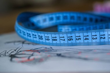 Tasarımcının çizimlerine göre şerit ölçüyorum. Terzi işi. Masanın üzerinde güzel elbiseler olan bir cereyan. Terzi konsepti. Yakın plan..