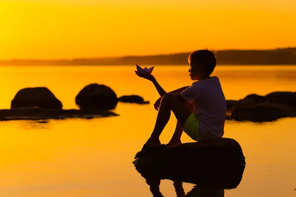 Liten Pojke Med Pappersskepp Händerna Vacker Orange Solnedgång Origami Floden — Stockfoto