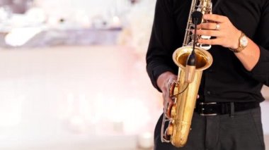 Saksafoncu eller saksafon çalıyor. Konser sahnesinde saksafonda çalan profesyonel saksafoncu.