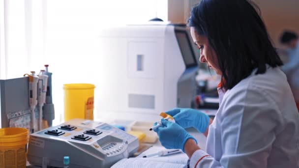 化学者として研究室で働いてる 血液検査のための現代的な機械の研究室で働く女性 — ストック動画