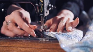 Kadın elleri dikiş arkasında. Terzi kadın dikiş makinesiyle elbise dikiyor.