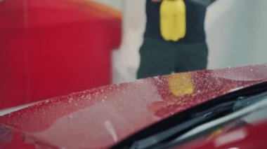 Benzin istasyonunda çamaşır makinesi kırmızı arabayı temizliyor. Araba yıkama köpüğüyle kaplı modern arabanın kaputunu kapat.