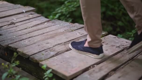 L'homme se promène sur un pont en bois. Jambes d'homme sur un vieux pont en bois à travers une petite rivière 