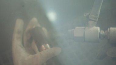 Fabrikada usta bir ressam. Fabrikada çalışan bir işçi barut kaplı bir silahla metal parçaları boyuyor.