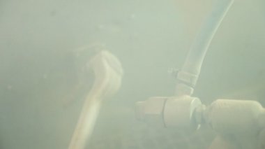 Üretim için fabrikadan ayrıntılar. İnşaat işçisi sprey tabancayla mekanik detayları boyuyor.