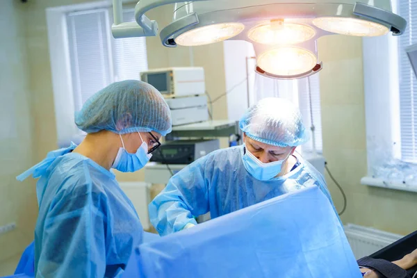 In surgery. Medical team performing operation in hospital operating theater. Working with surgical instruments.