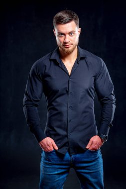 Stüdyoda, karanlık arka planda yakışıklı bir adamın portresi. Zarif bir genç adam. Modern saç stili olan seksi genç adam..