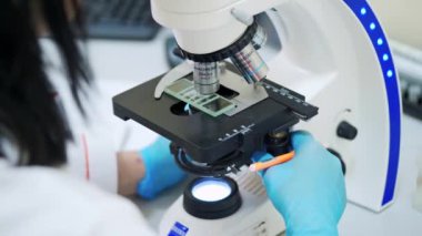 Kanın laboratuvar incelemesi. Laboratuvarda mikroskopla çalışan üniformalı kadın bilim adamlarına yakın çekim