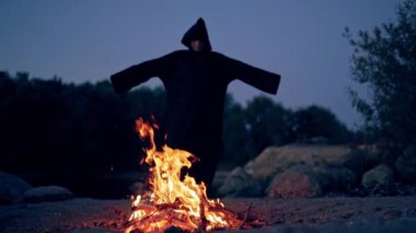 Şenlik ateşinin yanındaki siyahlı cadı. Şenlik ateşinin etrafında dolaşan mistik cadı