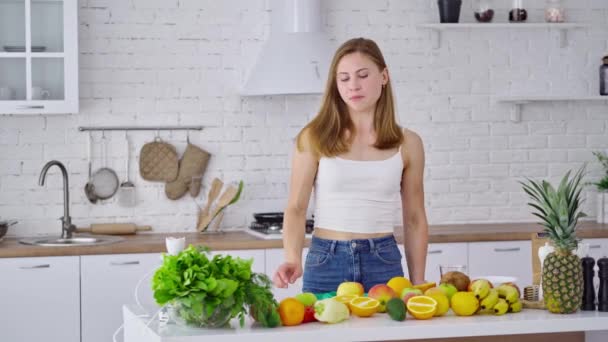 在家里笑家庭主妇 瘦小的年轻女子在清淡的厨房里吃着健康的食物 — 图库视频影像