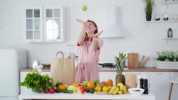 现代厨房里的年轻女人一个快乐的女孩在厨房里扔苹果的画像 — 图库视频影像