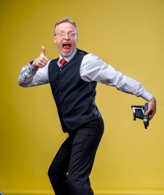 Funny senior man makes selfie of his ass on yellow background. Funny emotions.