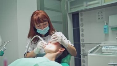 Diş sağlığı kliniği. Resepsiyon, hastanın muayenesi. Diş bakımı. Dişçi bir kız hastayı tedavi ediyor.