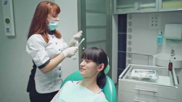 歯医者の女性が笑っている 患者との胃科医の仕事 あなたの笑顔を完璧にする — ストック動画