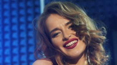 Parlak dudakları ve uzun kulakları olan güzel bir model mavi arka plandaki ses stüdyosunda mutlu bir şekilde şarkı söylüyor. Profesyonel şarkıcı kameraya bakar ve şarkı söyler. Ağır çekim. Yakın plan.