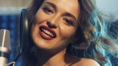 Mikrofonun yanında kameraya bakıp müzik stüdyosunda şarkı söyleyen profesyonel bir şarkıcının çekici yüzü. Güzel bir dişi ve mikrofon portresi. Yakın plan.
