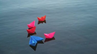 Mavi suda altı renkli kâğıt tekne ve üzerine ışık damlaları düşüyor. Nehirde yüzen güzel çocuk origami gemileri. Yakın plan.