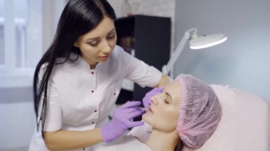 Güzel genç bir kadın dudaklarına iğne oluyor. Güzellik iğneleri ve kozmetoloji. Estetik ve estetik ameliyat.