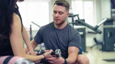 Fitness, spor, egzersiz ve halter konsepti - genç kadın ve spor salonunda kaslarını esneten halterli kişisel antrenör