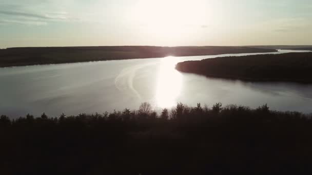 Rivière large et calme est situé entre les champs et les forêts au lever du soleil. Une petite maison se dresse sur la rive de la rivière avec une belle vue sur la campagne. Vue aérienne .