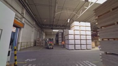 Depocu yükleyiciyi yerleştirir ve depodaki kargoyu almak için hidrolik çatalları kaldırır..