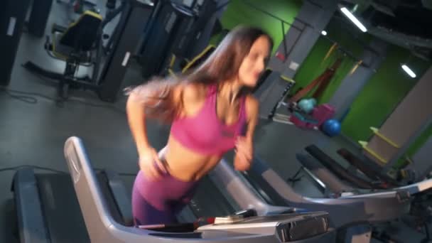 Glückliche Gesichter positiver Frauen in lila Sportbekleidung laufen auf einem Laufband im Fitnessstudio. Sportlich lächelnde Mädchen beim Training auf einer Rennbahn im modernen Fitnesscenter