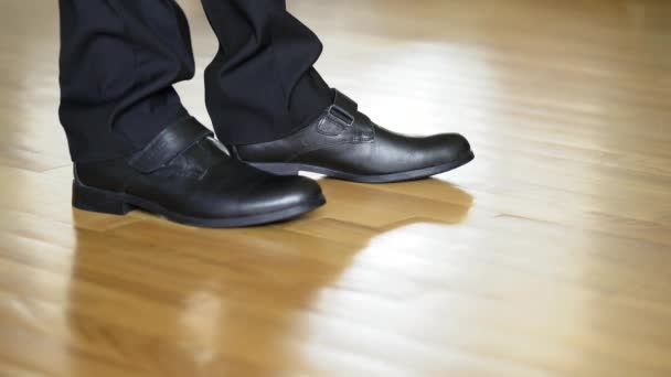 人の足は黒い靴がかかとに立ち 木製の床に行くことを示す ダンスシューズの中の若い男の足 — ストック動画